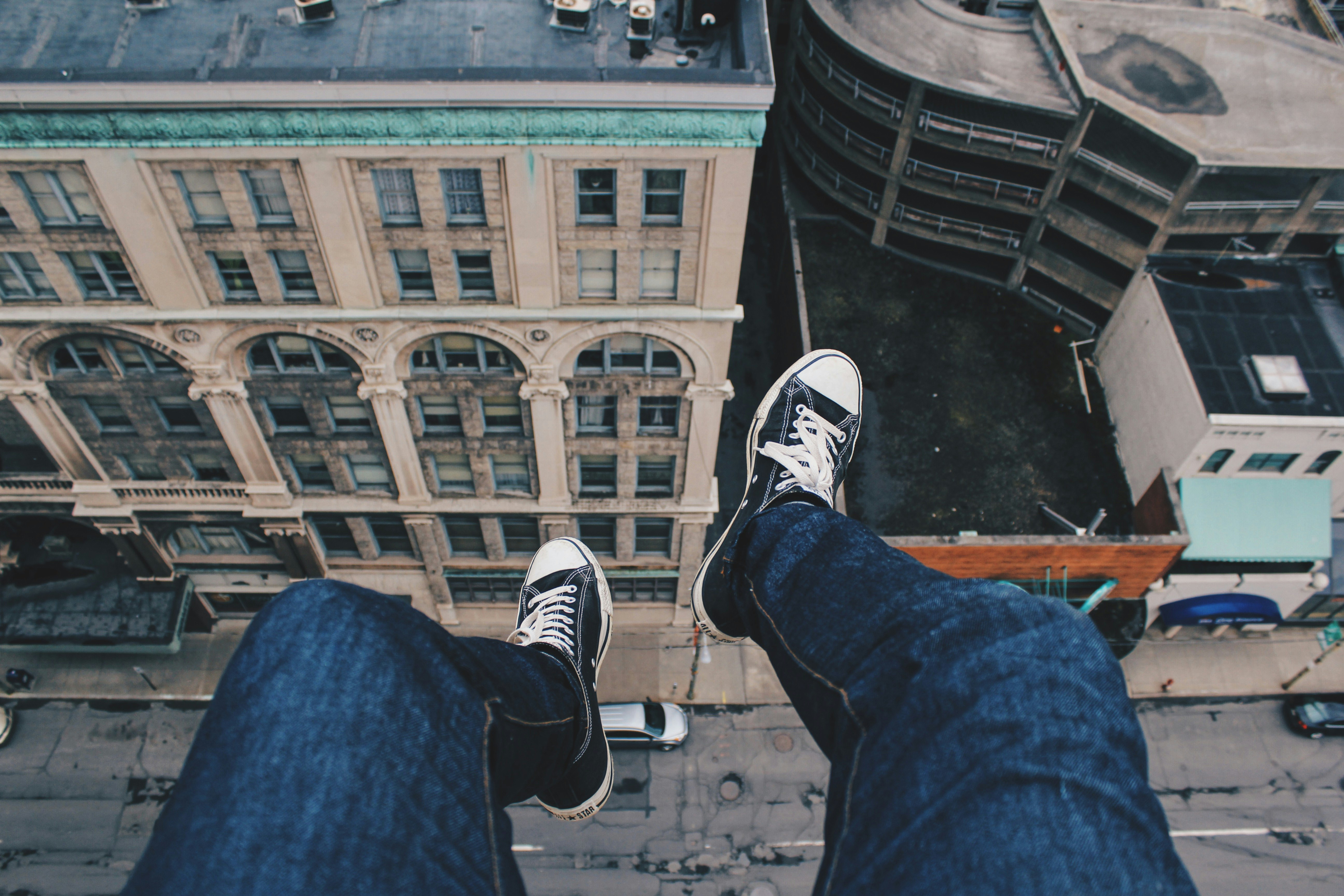 person sitting on cliff above building